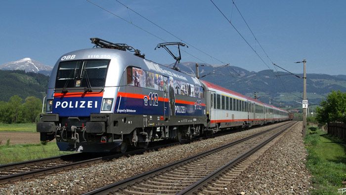 La Taurus 1116-250 austriaca recuerda el n�mero de emergencias para llamar a la Polic�a, remolcando un tren de Larga Distancia con coches de viajeros y portacoches.