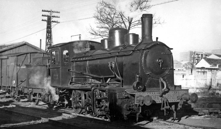 Perspectiva de la locomotora de vapor 030-2531 en Salamanca con un vagn cerrado de mercancas, de madera. Tras ella se ven edificios de viviendas. Archivo Histrico Ferroviario FE-0009-015